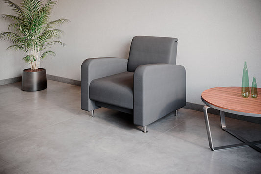 Sillón Profile de 1 plaza en tapizado gris, junto a mesa lateral y planta decorativa